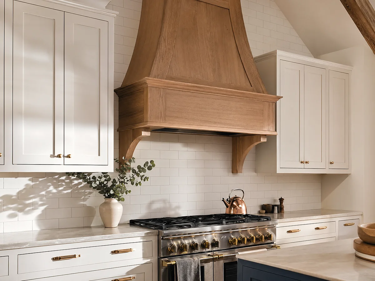 Custom white oak range hood with corbels above inset shaker kitchen cabinetry