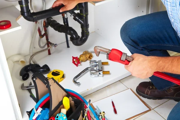 Plumber repairing the pipes under a kitchen sink