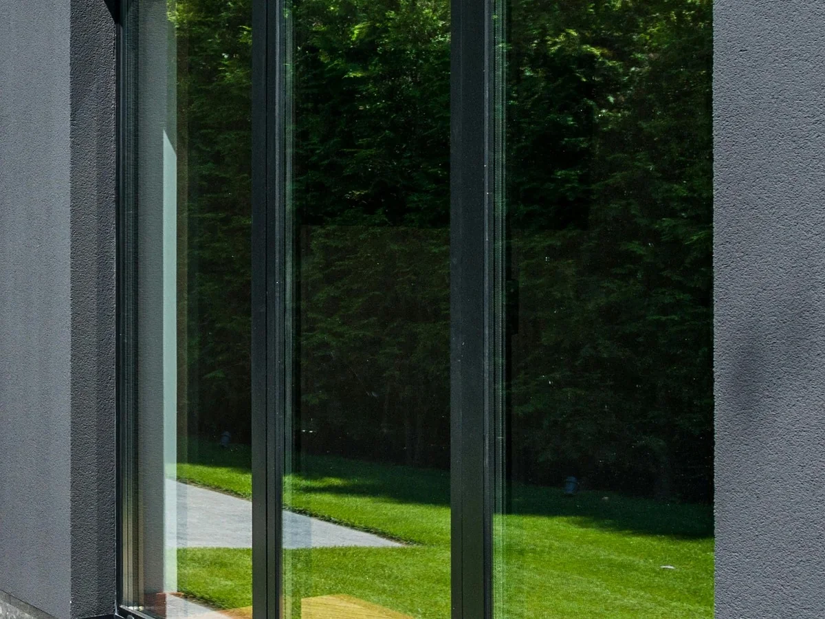 Tinted sliding glass doors on a home reflecting the backyard lawn