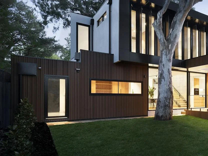 Modern home exterior finished in dark vertical board siding at dusk